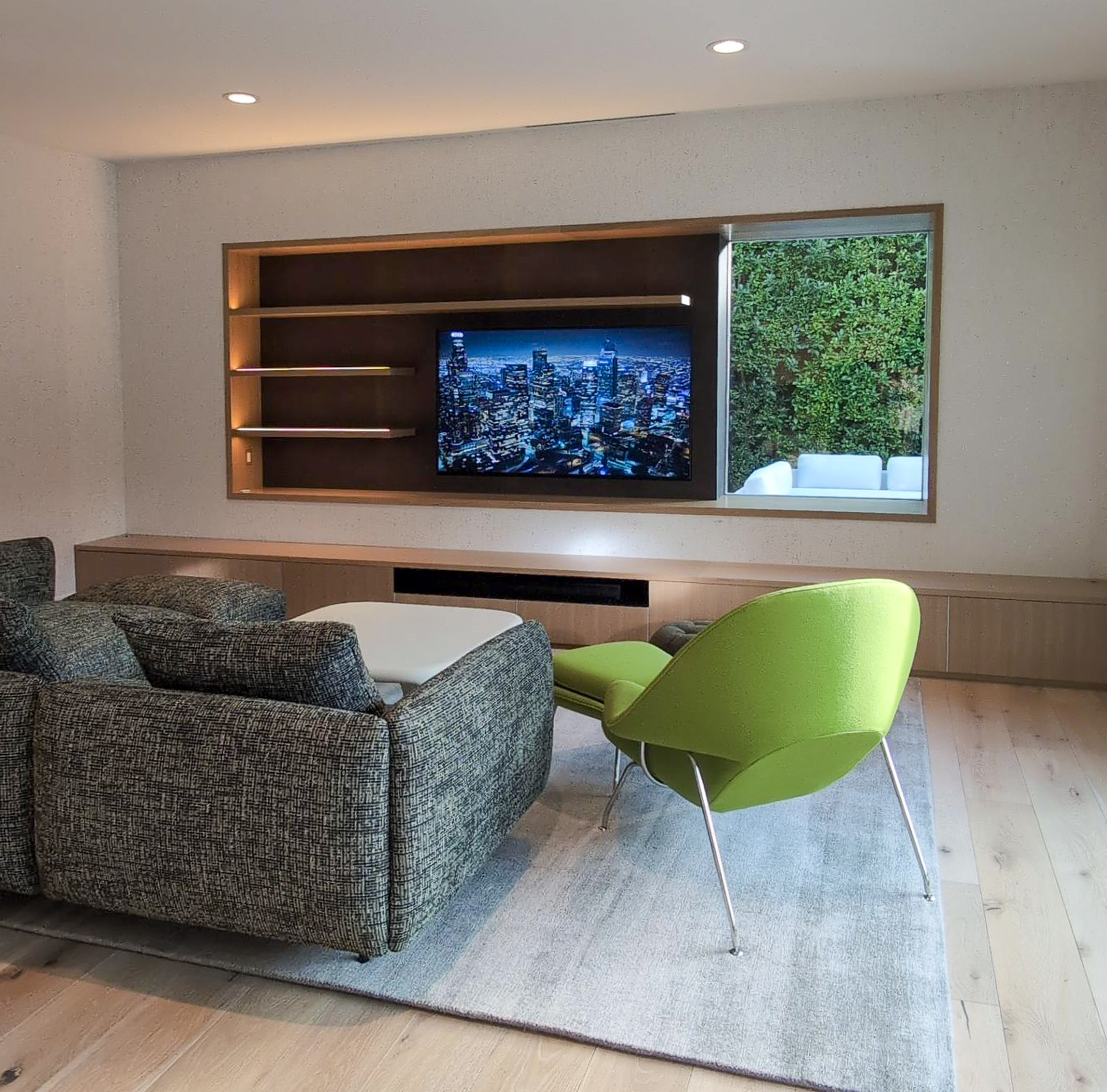 Palm Springs Living & Kitchen Remodel — living room with custom built-in entertainment wall, LED shelving, green womb chair and oak floors