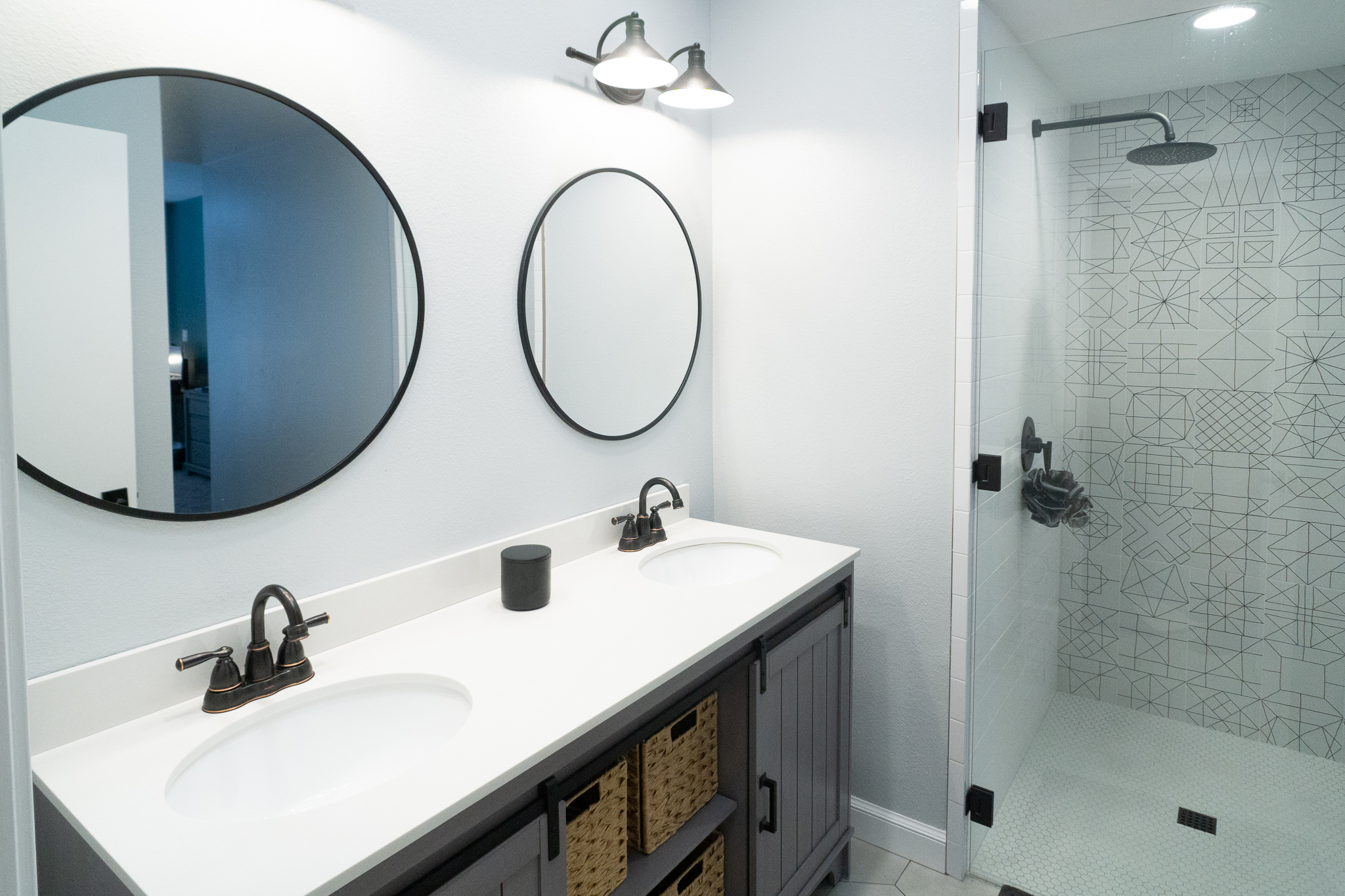 Palm Desert Whole-Home Renovation — double vanity bathroom with dual round mirrors and geometric shower tile