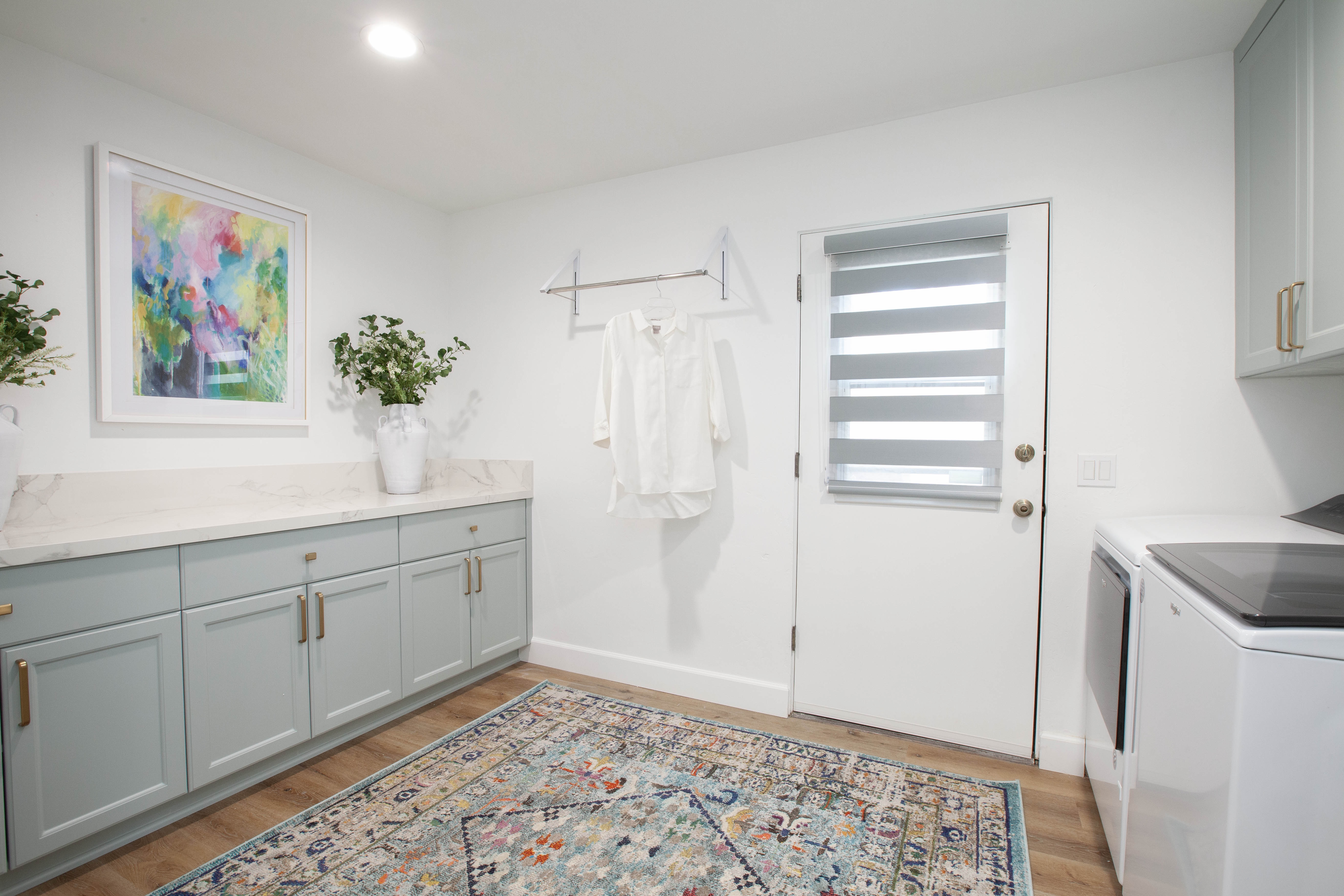 Room Addition & Whole-Home Renovation — laundry room with sage cabinets, hanging rod and patterned rug